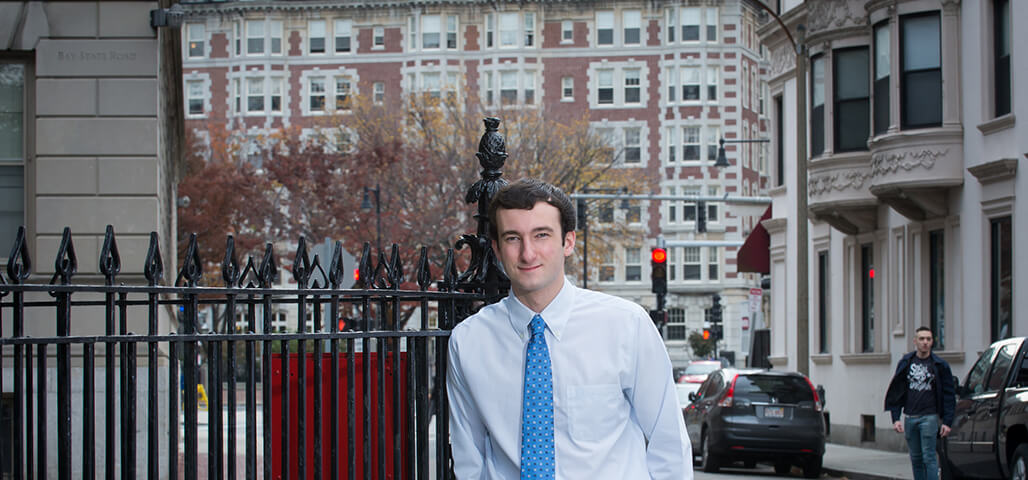 A Business Management Associate Degree student in business attire, outisde (city in the background).