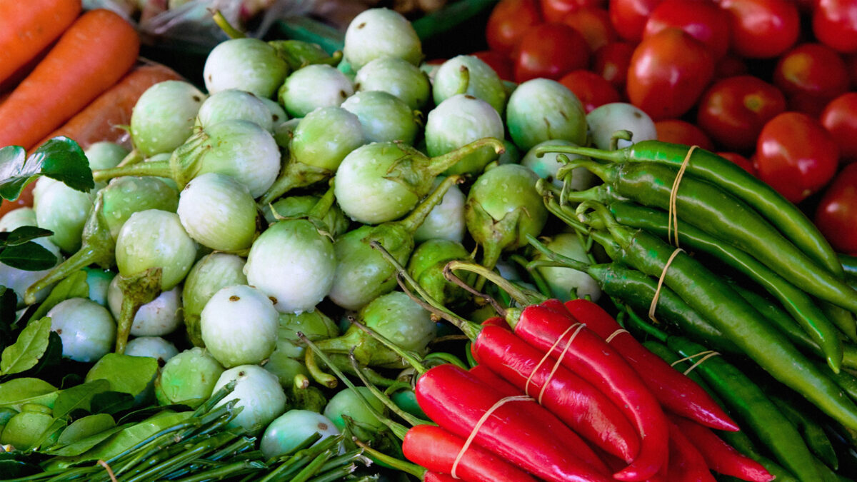 A photo of some fruit and veggies, including chili peppers, onions, tomatoes