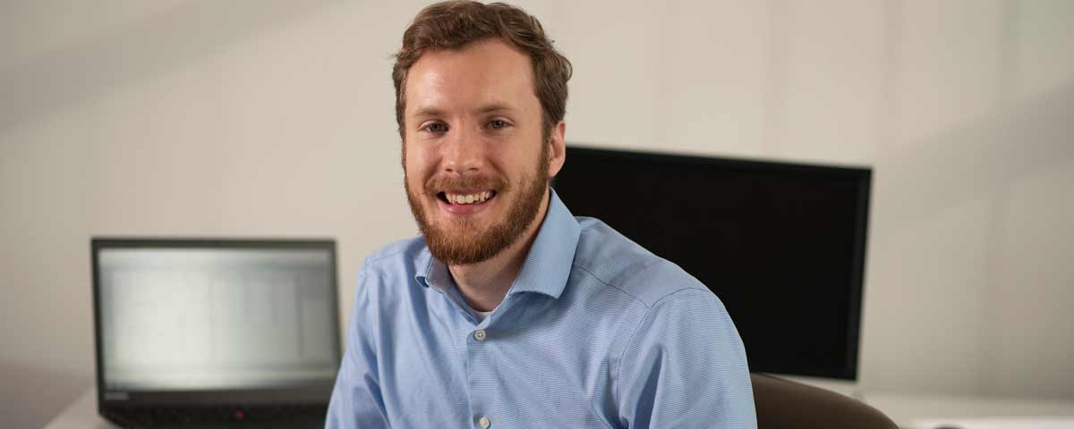 Computer science student Alex Bochman sitting in front of computers.