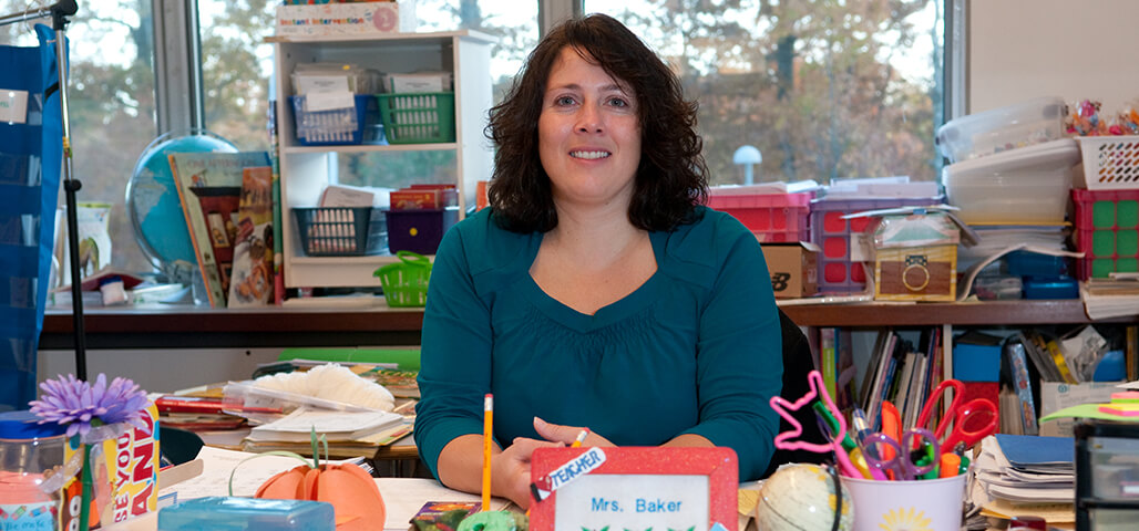 An Educational Studies student teacher in an elementary classroom surrounded by books and art supplies.