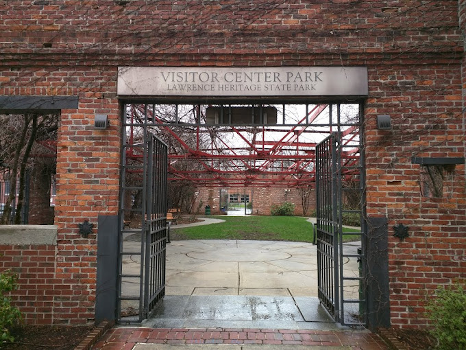 A photo of the Visitor Center at the Lawrence Heritage Center, a gateway with a green park behind it