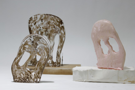 Three glass and plastic monuments, two are brown swirls in clear glass, another one is solid light pink. All have rounded edges, smooth surfaces, with two oblong holes cut out in the center.