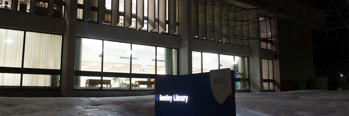 Outside view of the Bentley Library at night with inviting lights blazing through the windows.