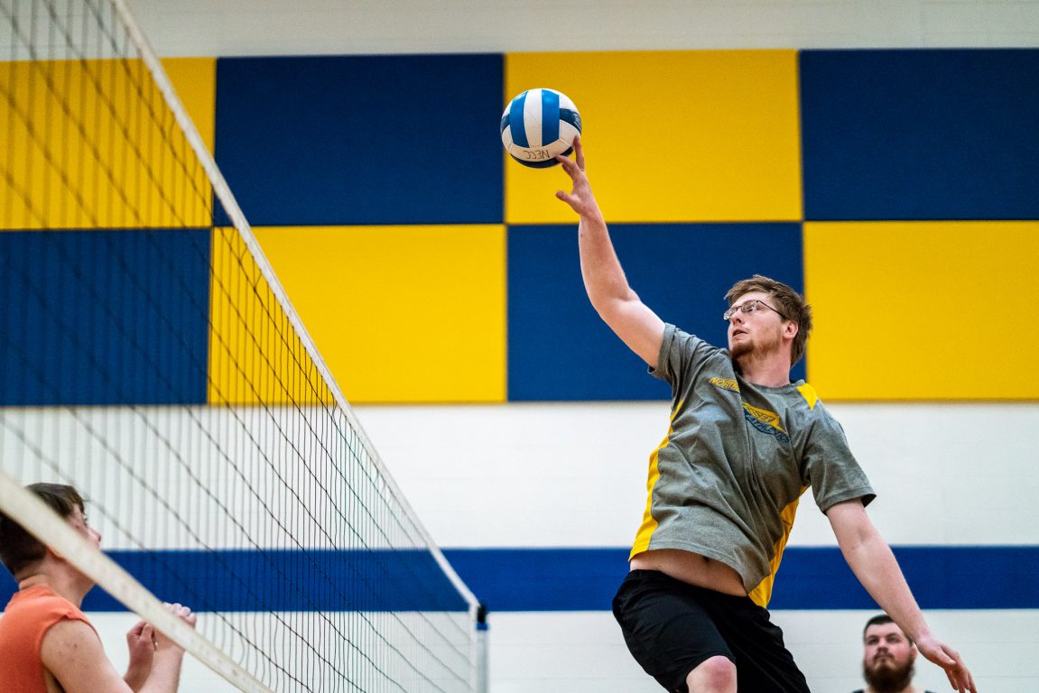 NECC student, Matthew Day leaps up to knock a volleyball over a net