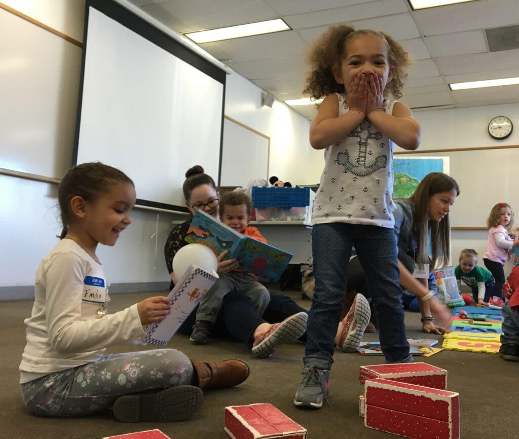 Children and parents reading or playing in a classroom.