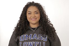 pictured: a smiling young woman wearing a UMASS Lowell sweatshirt