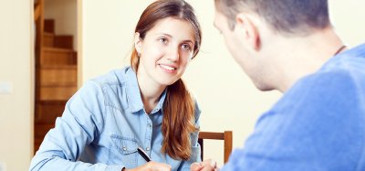 A student in the Public Health Associate Degree program listening to a client and taking notes.