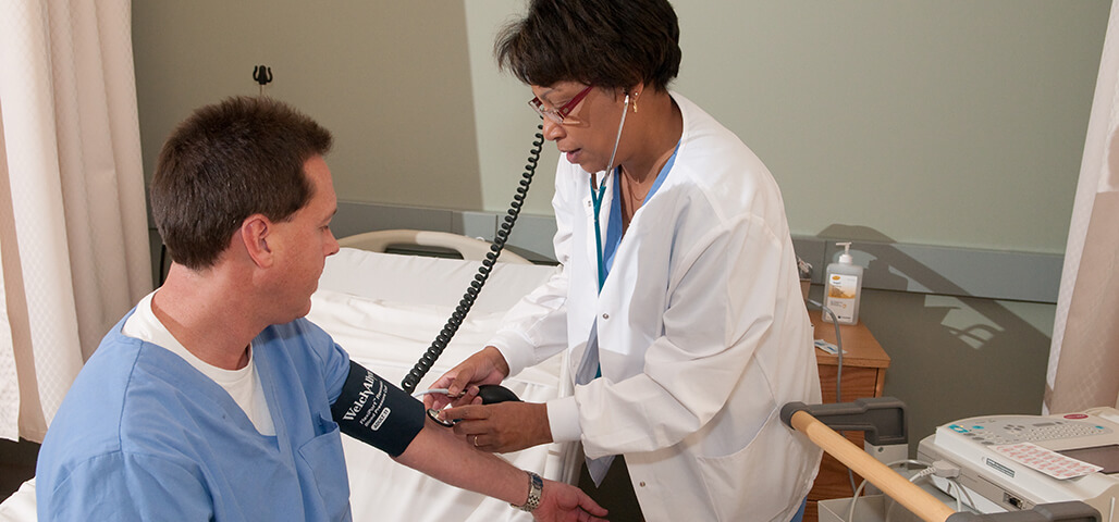 A student in the Healthcare Technician certificate program practicing her skills with a mock patient.