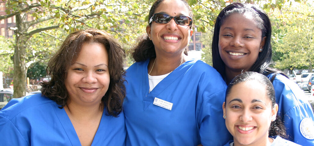 Four Nursing Advanced Placement students, wearing uniforms, looking very happy and proud.