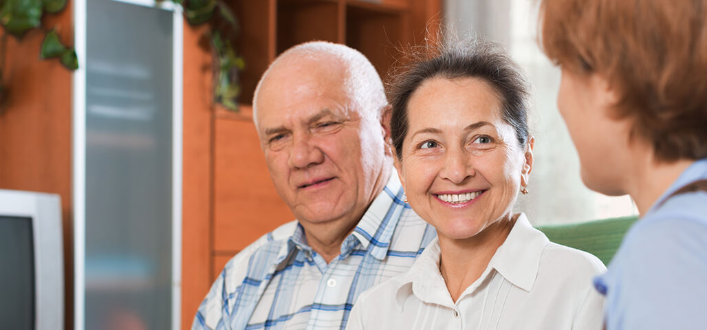 An older couple listen to a student practing her skills in the Public Health Associate Degree program.