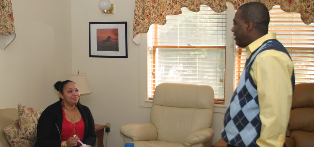 A Community Support Human Services Practitioner Certificate student in a home-office-type room makes cordial conversation with a young woman.