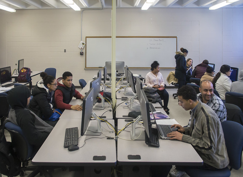A computer lab with multiple students working on the computers. 