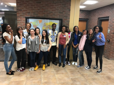 Group of students from variouse countries with VP of Lawrence campus in front of world map