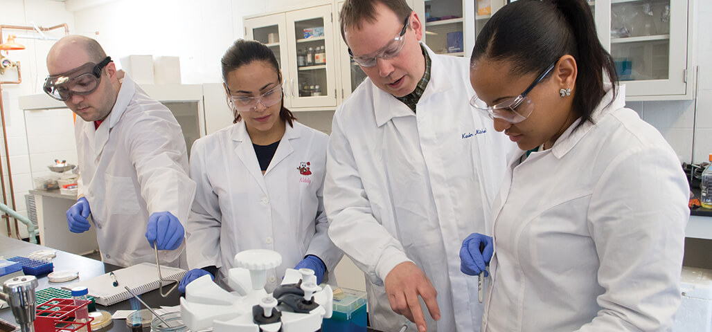 Three Laboratory Science degree students run testing under the close watch of a faculty member