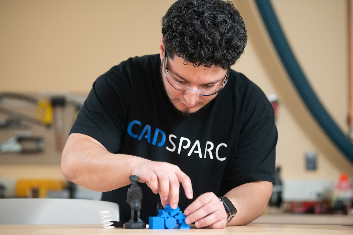 jonathan works on a 3d printed model. he is wearing a tshirt with the CADSPARC logo and saftey glasses