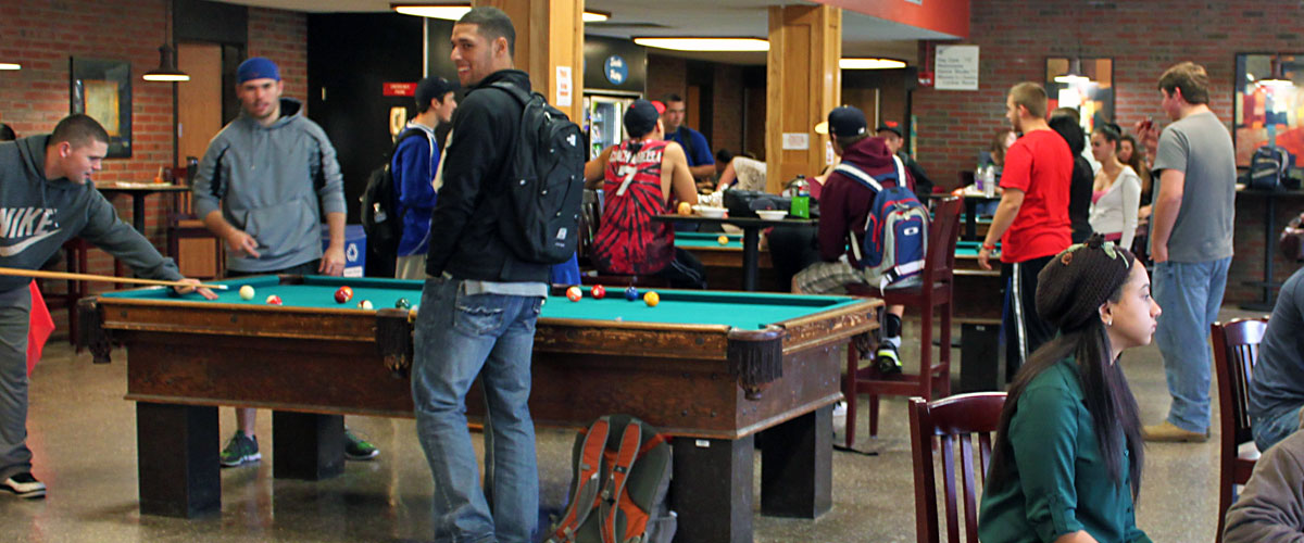 Students playing pool, standing, sitting anding talking, in the Sport and Fitness Center Lobby