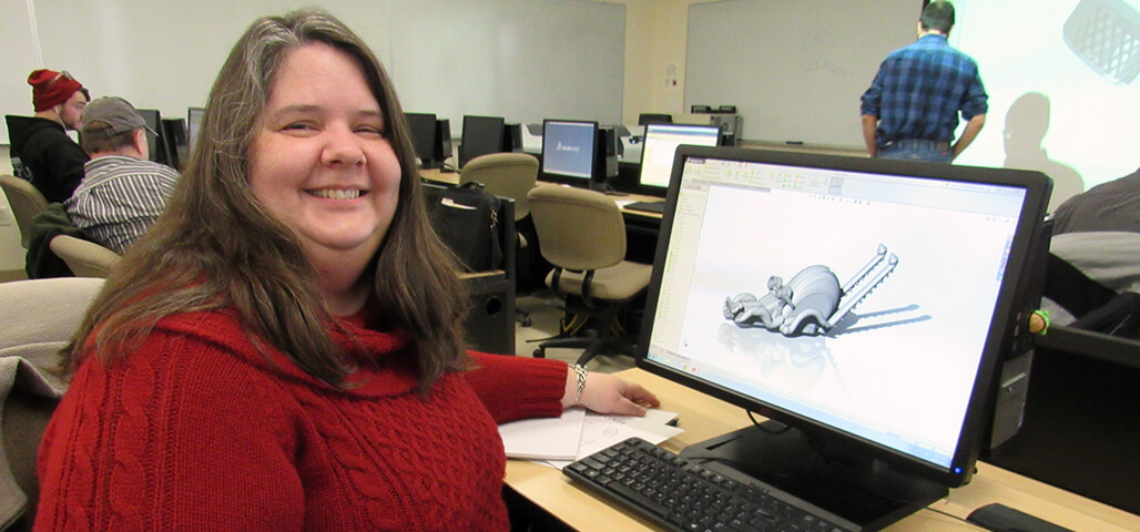 A Computer Aided Drafting student in a computer classroom displaying her work on a CAD program.